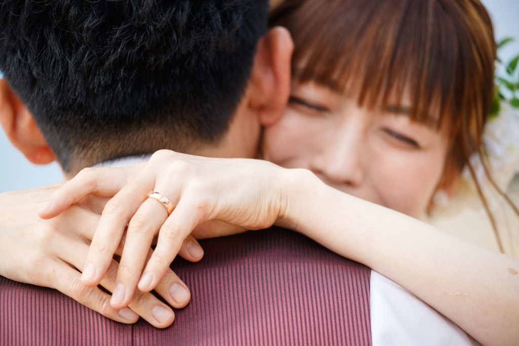 糸島の海岸で撮影した洋装前撮り写真 新郎新婦が抱き合うウェディングフォトのクローズアップ
